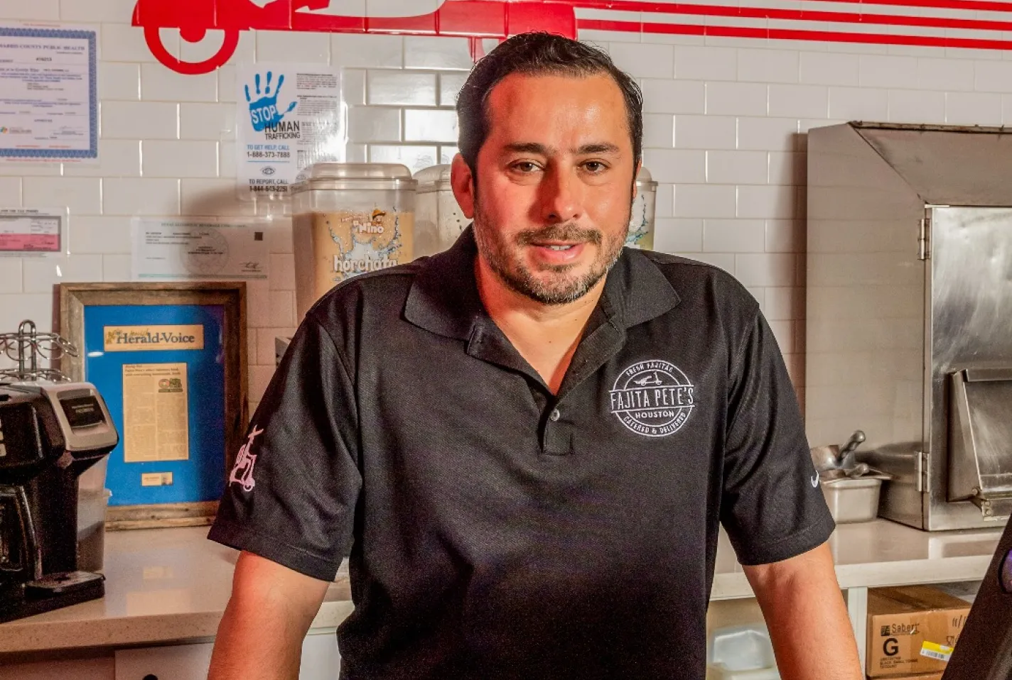 Pedro Mora standing inside Fajita Pete’s restaurant wearing a black company polo shirt.